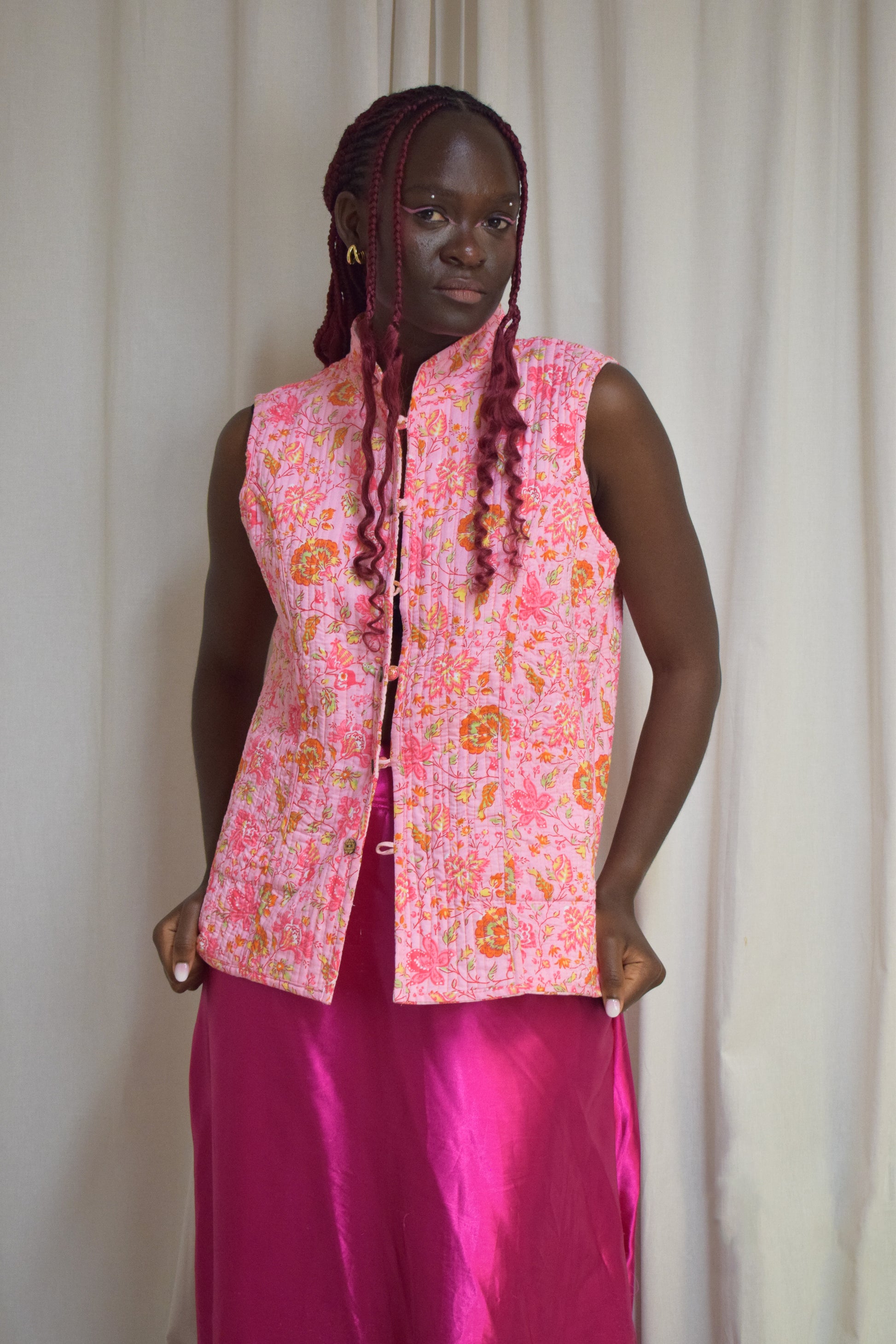 Female model posing in a pink vest and pink skirt.
